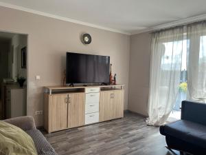 a living room with a flat screen tv on a wooden cabinet at Schöne Wohnung Mit Dem Garten in Jübek