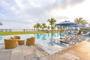 a pool at a resort with chairs and umbrellas at Aqua Vista Hoi An Beachfront Villas in Hoi An