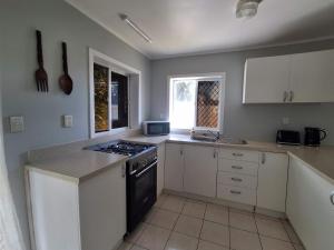 a kitchen with white cabinets and a stove top oven at Akaroa Hideaway in Avarua