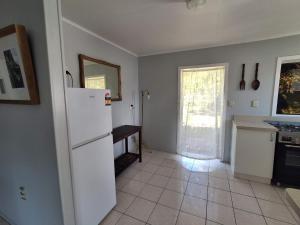 a kitchen with a white refrigerator and a tile floor at Akaroa Hideaway in Avarua +2 photos
