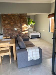 a living room with a couch and a brick wall at Pule's Home & Studio Apartments in Maseru