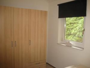 Recreatiebungalow Lochem في لوخيم: غرفة نوم بها نافذة وخزانة ونافذة