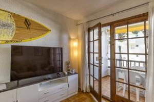 a living room with a television and a surfboard on the wall at Amarres con Piscina in L'Escala