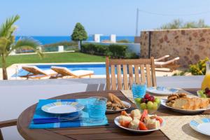 a wooden table with plates of food on it at Deep Blue Villa in Lachania