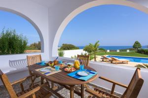 a dining room with a table and chairs and a pool at Deep Blue Villa in Lachania +47 photos