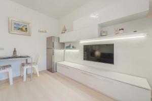 a white living room with a television and a table at Marina Vip Anna in Procchio +36 photos