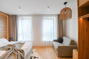 a bedroom with a bed and a chair and window at Hotel Monínec - Depandance Apartmány in Moninec