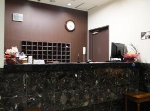 a reception desk with a clock on a wall at Hotel Trend Funabashi in Funabashi