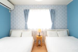 two beds in a room with blue walls and a window at 古宇利島まで車で10分の星降るやんばるテラス海まで徒歩3分のは1棟貸 in Nago