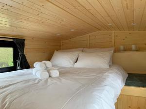 a bed in a wooden room with three pillows on it at Lahod Tiny House by Tiny Away in Žalec