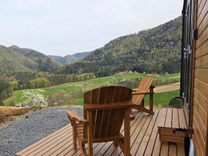 a wooden deck with a chair and a view of the mountains at Lahod Tiny House by Tiny Away in Žalec