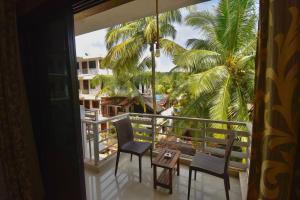 a balcony with chairs and a table and palm trees at Da Down Resort & Hotel in Candolim
