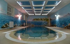 a swimming pool in a room with a painting on the wall at Hotel Gloria in Kostanay