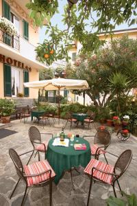 un patio con mesa, sillas y sombrilla en Hotel Villa Bianca, en Laigueglia