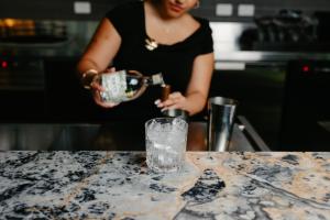 a woman pouring a drink into a glass on a counter at voco Auckland City Centre by IHG in Auckland