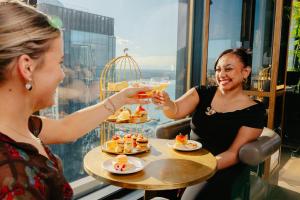 two women sitting at a table with drinks at voco Auckland City Centre by IHG in Auckland