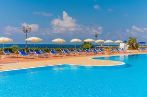 a swimming pool with chairs and umbrellas at VOI Florio Resort in Cinisi