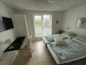 a bedroom with a bed and a desk and a window at Sov Godt i Arnborg Bed & Breakfast in Arnborg
