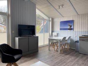 a dining room with a table with chairs and a television at Strandhaus Freibeuterweg 24 in Priwall