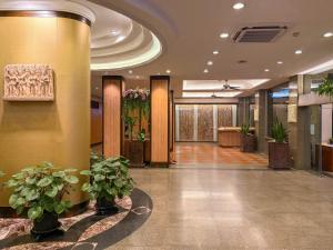 a lobby with potted plants in a building at Golden Beach Hotel Pattaya in Pattaya +119 photos