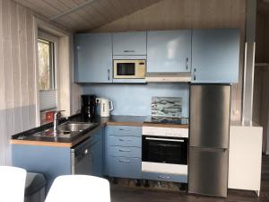 a kitchen with blue cabinets and a sink and microwave at Strandhaus Freibeuterweg 24 in Priwall +10 photos