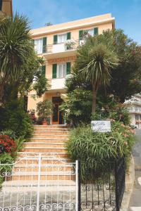 a building with stairs and palm trees in front of it at Hotel Villa Bianca in Laigueglia