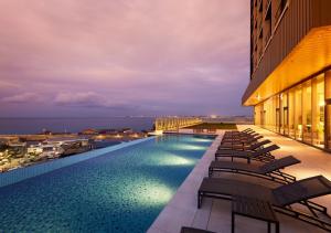 a swimming pool on the roof of a building with chairs at HOTEL AlaCOOJU OKINAWA in Urazoe