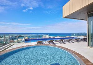 a swimming pool on a balcony with a view of the ocean at HOTEL AlaCOOJU OKINAWA in Urazoe