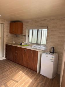 a small kitchen with a white refrigerator and wooden cabinets at Batroun Souq, Perfect location, 1 Bedroom in Batroûn