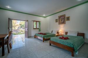 a bedroom with two beds and a table and a desk at Argasoka Bungalows in Ubud