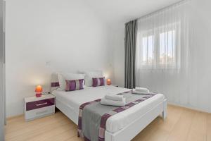 a white bedroom with two beds and a window at LotusPoolApart in Premantura +95 photos