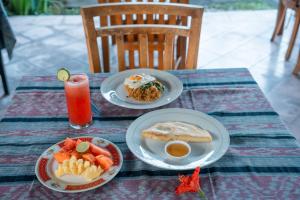 a table with two plates of food and a drink at Argasoka Bungalows in Ubud