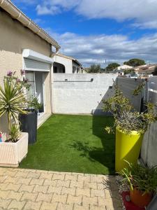 a small backyard with grass and potted plants at Chez Fabrice in Lunel