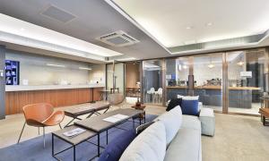 ein Wohnzimmer mit Sofa, Tischen und einer Bar in der Unterkunft Bay Hound Hotel in Busan