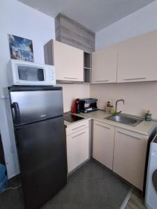 a kitchen with a black refrigerator and a microwave at Студио C19 в к-с Blue Bay Palace in Pomorie