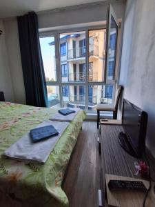a bedroom with a bed and a desk and a window at Студио C19 в к-с Blue Bay Palace in Pomorie
