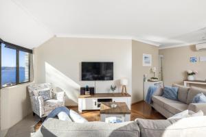 a living room with two couches and a tv at Tranquil Escape - Koala Hotspot - 2 Bed 2 Bath Apt Spectacular Sea Views in Soldiers Point +27 photos