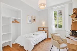 a white bedroom with a bed and a chair at Rooms in Villa Agra in Agra