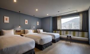 ein Hotelzimmer mit zwei Betten und einem Fenster in der Unterkunft Bay Hound Hotel in Busan