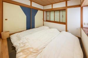 a small bedroom with a white bed in it at BASE CAMP Kitakaruizawa in Naganohara