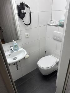 a white bathroom with a toilet and a sink at Hotel Rhein INN in Remagen +15 photos