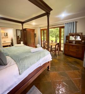 a bedroom with a large bed and a table at Luxury Country Retreat Hot Tub & Farm Views in Dullstroom