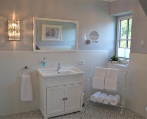 a white bathroom with a sink and a mirror at Reetdachhaus Seestern in Garding +57 photos
