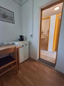 a kitchen with a table and a door to a bathroom at Benkovac sobe in Benkovac