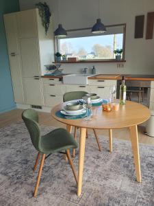 a kitchen with a wooden table and green chairs at Het Groene uitzicht in Bantega