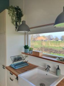 a kitchen with a white sink and a window at Het Groene uitzicht in Bantega