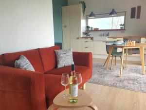 a living room with a red couch and two wine glasses at Het Groene uitzicht in Bantega