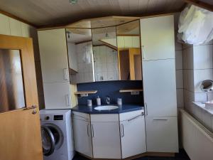a bathroom with a sink and a washing machine at Ferienwohnung Czanderl in Dießen am Ammersee +15 photos