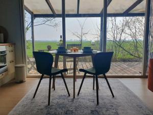 a dining room table with two chairs in front of a window at Het Groene uitzicht in Bantega +26 photos