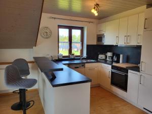 a kitchen with white cabinets and a black counter top at Ferienwohnung Czanderl in Dießen am Ammersee